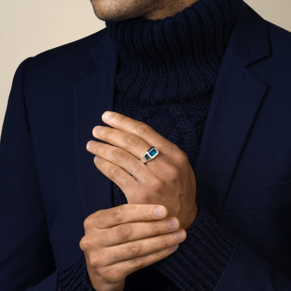 Man wearing a dark blue turtleneck and navy suit blazer with a sterling silver london blue topaz ring on his hand